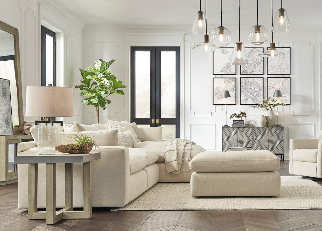 Modern living room with beige sectional sofa, ottoman, and decorative elements.